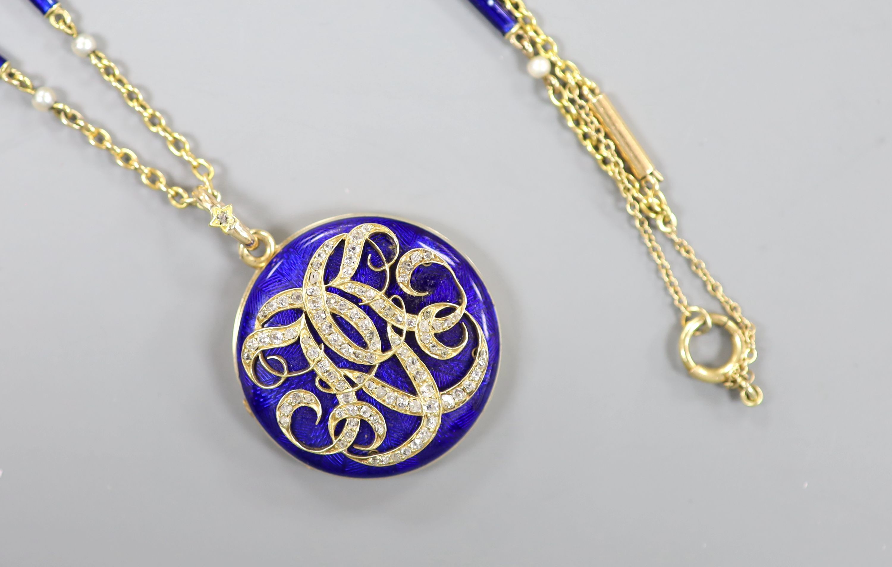 A yellow metal, blue enamel and rose cut diamond set monogrammed circular locket (a.f.) 29mm, on a 9k, seed pearl and blue enamel baton link chain, 48cm